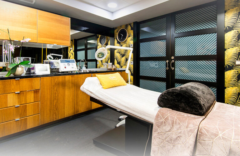 Sala de tratamiento de centro estético Aroma en Benalmádena con paredes en tonos oscuros y muebles de madera